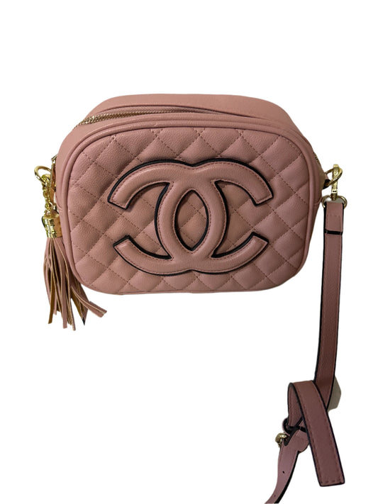 Pink quilted handbag with a brand logo on a white stand against a light background