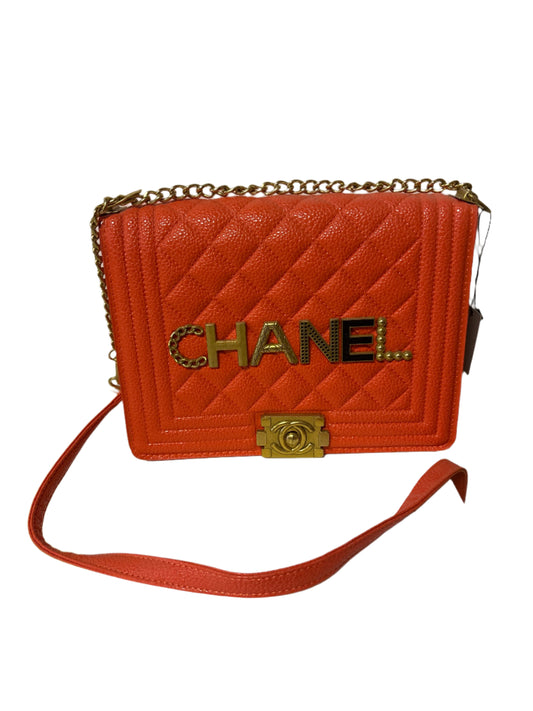 Orange quilted Chanel handbag with gold chain and clasp on a white background
