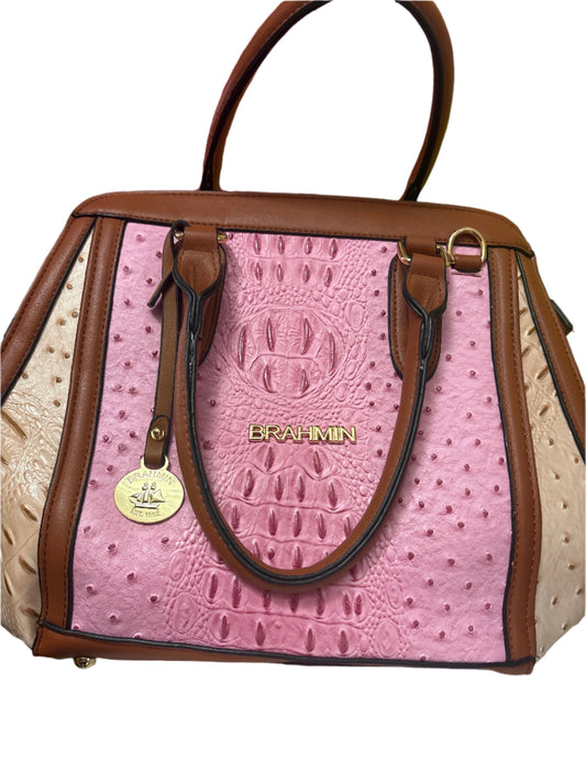 Pink textured handbag with brown accents on a green surface
